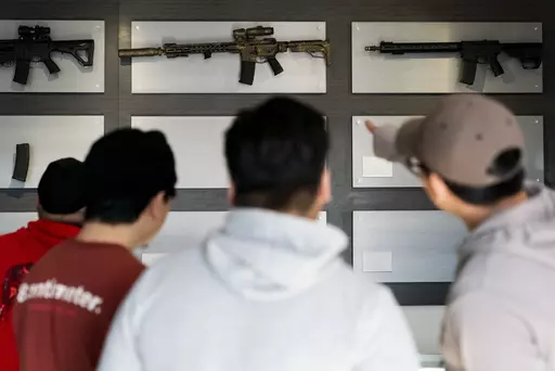 Customers look at AR-15-style rifles on a mostly empty display wall at Rainier Arms Friday, April 14, 2023, in Auburn, Wash. as stock dwindles before potential legislation that would ban future sale of the weapons in the state. House Bill 1240 would ban the future sale, manufacture and import of assault-style semi-automatic weapons to Washington State and would go into immediate effect after being signed by Gov. Jay Inslee. (AP Photo/Lindsey Wasson)