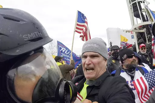 In this image from video, Alan William Byerly, center, attacks an Associated Press photographer during a riot at the U.S. Capitol in Washington, Jan. 6, 2021. On Sunday, Oct. 9, 2022, federal prosecutors recommended a prison sentence of nearly four years for Byerly, of Pennsylvania, who pleaded guilty to assaulting the AP photographer and using a stun gun against police officers during a mob's attack on the U.S. Capitol. (AP Photo/Julio Cortez, File)