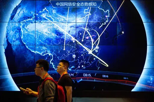 In this Sept. 12, 2017, file photo, attendees walk past an electronic display showing recent cyberattacks in China at the China Internet Security Conference in Beijing. Cybersecurity and space are emerging risks to the global economy, adding to existing challenges posed by climate change and the coronavirus pandemic, the World Economic Forum said in a report Tuesday, Jan. 11, 2022. (AP Photo/Mark Schiefelbein, File)