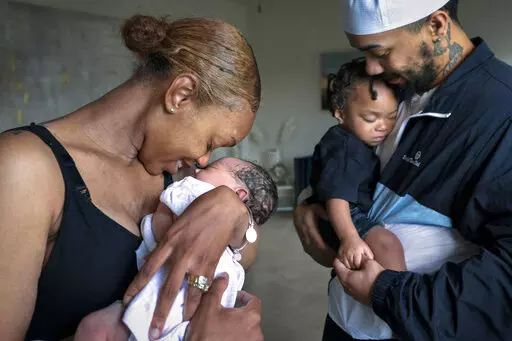 Aaliyah Wright, 25, of Washington, nuzzles her newborn daughter Kali, as her husband Kainan Wright, 24, of Washington, holds their son Khaza, 1, as he falls asleep, during a visit to the children's grandmother in Accokeek, Md., Tuesday, Aug. 9, 2022. A landmark social program is being pioneered in the nation’s capital. Coined “Baby Bonds,” the program is designed to narrow the wealth gap. The program would provide children of the city’s poorest families up to $25,000 when they reach adul