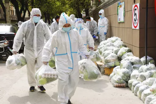In this photo released by Xinhua News Agency, volunteers carry daily necessities for residents in Fengxian District in eastern China's Shanghai city on Monday, March 28, 2022. China began its most extensive coronavirus lockdown in two years Monday to conduct mass testing and control a growing outbreak in Shanghai as questions are raised about the economic toll of the nation's "zero-COVID" strategy. (Wang Yanting/Xinhua via AP)
