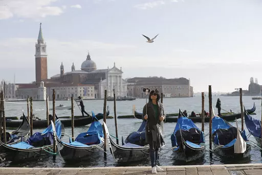 A tourist takes a selfie in St. Mark's Square in Venice, Italy, Nov. 12, 2016. Starting in January, Venice will oblige day-trippers to make reservations and pay a fee to visit the historic lagoon city. On many days, the heart of Venice is overwhelmed by visitors, who often far outnumber residents. Venice officials on Friday unveiled new rules for day-trippers, which go into effect on Jan. 16, 2023. (AP Photo/Luca Bruno, File)