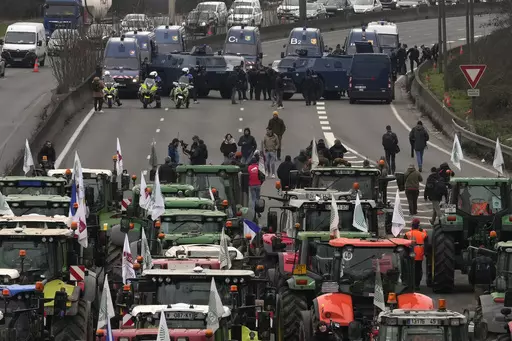 Tractors face military vehicles on a blocked highway, Wednesday, Jan. 31, 2024 in Chilly-Mazarin, south of Paris. Farmers have captured France's attention by showering government offices with manure and besieging Paris with traffic-snarling barricades of tractors and hay bales. Protesters say it's becoming harder than ever to make a decent living from their fields, greenhouses and herds. (AP Photo/Thibault Camus)
