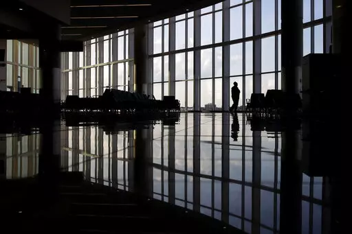 In this June 1, 2020 file photo, a woman looks through a window at a near-empty terminal at an airport in Atlanta. An influential health guidelines group says U.S. doctors should regularly screen adults for anxiety. It’s the first time the U.S. Preventive Services Task Force has recommended anxiety screening in primary care for adults without symptoms. The report released Tuesday, Sept. 20, 2022 is open for public comment until Oct. 17. (AP Photo/Charlie Riedel, File)