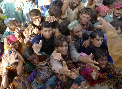 Displaced families, who fled their flood-hit homes, jostle to get relief aid distributed by soldiers of Pakistan rangers, in Dera Allahyar, in Jaffarabad, a district of southwestern Balochistan province, Saturday, Sept. 17, 2022. The devastating floods affected over 33 million people and displaced over half a million people who are still living in tents and make-shift homes. The water has destroyed 70% of wheat, cotton and other crops in Pakistan. (AP Photo/Zahid Hussain)