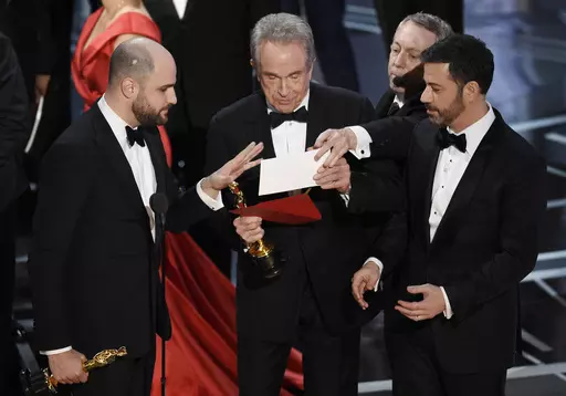 "La La Land" producer Jordan Horowitz, left, presenter Warren Beatty, center, and host Jimmy Kimmel right, look at an envelope announcing "Moonlight" as best picture at the Oscars on Sunday, Feb. 26, 2017, in Los Angeles. It was originally announced mistakenly that "La La Land" was the winner. (Photo by Chris Pizzello/Invision/AP, File)