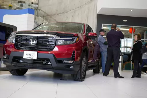 Customers confer with a salesperson as a 2022 Ridgeline pickup truck sits on the showroom floor of a Honda dealership, Friday, April 15, 2022, in Highlands Ranch, Colo. (AP Photo/David Zalubowski, File)