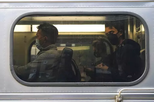 People wear face masks as they sit in a Metra train at the Metra Arlington Heights station Thursday, Sept. 15, 2022, in Arlington Heights, Ill. President Joe Biden said Thursday a tentative railway labor agreement has been reached, averting a potentially devastating strike before the pivotal midterm elections. (AP Photo/Nam Y. Huh)