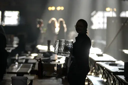 A waitress prepares beer mugs in the Augustiner marquee for the start of the 189th 'Oktoberfest' beer festival in Munich, Germany, on Sept. 21, 2024. (AP Photo/Matthias Schrader)
