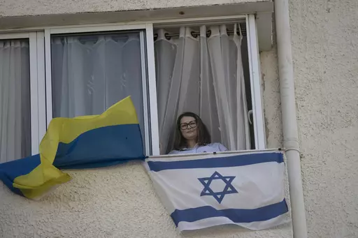 Tatyana Prima, who fled Mariupol, Ukraine, poses for a portrait with her national flag and the Israeli flag she displays outside of her apartment window in Ashkelon, southern Israel, Wednesday, Nov. 8, 2023. She thought she'd left the bombs behind when she fled after Russian troops decimated her city. Risking her life, the 38-year-old escaped with her injured husband and young daughter, bringing the family to safety in southern Israel. Yet the calm she was slowly regaining shattered on Oct. 7, w