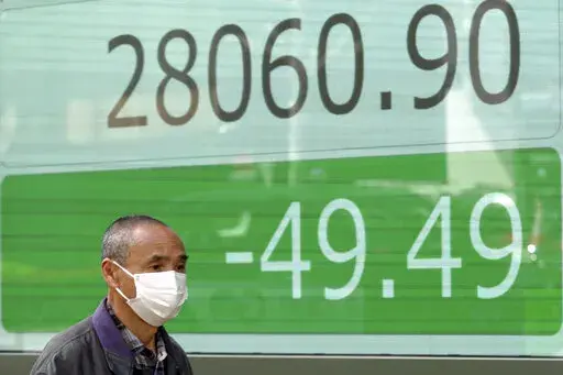 A man wearing a protective mask walks in front of an electronic stock board showing Japan's Nikkei 225 index at a securities firm Friday, March 25, 2022, in Tokyo. Asian stock markets fell Friday after Western governments promised new sanctions on Russia and President Vladimir Putin tried to prop up Moscow's sinking ruble by threatening to require Europe to use it to pay for gas exports. (AP Photo/Eugene Hoshiko)