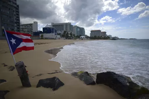 A Puerto Rican flag flies on an empty beach at Ocean Park, in San Juan, Puerto Rico, Thursday, May 21, 2020.  Puerto Rico’s nearly five-year bankruptcy battle was resolved Tuesday, Jan. 18, 2022, after a federal judge signed a plan that slashes the U.S. territory’s public debt load as part of a restructuring and allows the government to start repaying creditors. (AP Photo/Carlos Giusti, File)