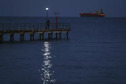 A man walks on a dock as a ship seen in the background in southern port city of Limassol, Cyprus, Friday, Feb. 23, 2018. Cyprus is working out with partners in the European Union and the Middle East the logistics to establish a sea corridor to deliver a stream of vital humanitarian aid to Gaza from the island’s main port of Limassol once the situation on the ground permits it. (AP Photo/Petros Karadjias, File)