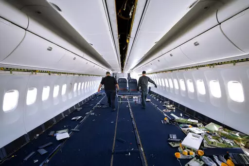 Engineers carry out passenger seats as they work on the conversion of a Boeing 767 passenger plane to a cargo plane at the Israel Aerospace Industries in Lod, near Tel Aviv, Israel, Feb. 13, 2022. With the global airline industry in a slump, Israel's state-owned aerospace company is cashing in on the pandemic-driven growth in e-commerce by converting grounded passenger planes into cargo jets. (AP Photo/Oded Balilty)