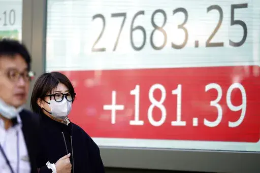People walk in front of an electronic stock board showing Japan's Nikkei 225 index at a securities firm Thursday, Feb. 16, 2023, in Tokyo. Asian shares edged higher Thursday, cheered by a stronger than expected reading on U.S. retail sales that set off a rally on Wall Street. (AP Photo/Eugene Hoshiko)