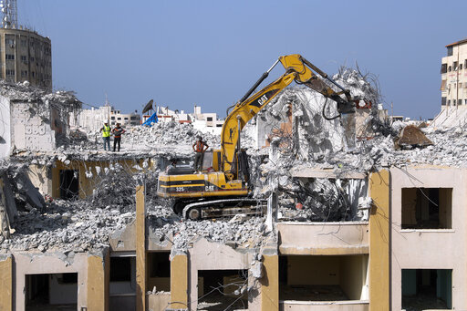 Palestinian workers use a backhoe to break and remove parts of the Al-Jawhara building, that was damaged in Israeli airstrikes during Israel's war with Gaza's Hamas rulers last May, in the central al-Rimal neighborhood of Gaza City, Nov. 16, 2021. The Gaza Strip has few jobs, little electricity and almost no natural resources. But after four bruising wars with Israel in just over a decade, it has lots of rubble. Local businesses are now finding ways to cash in on the chunks of smashed concrete, 