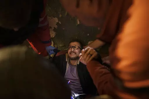 Vadim Krikun is treated in the hallway of his apartment building after a Russian attack in Kharkiv, Ukraine, Friday, April 15, 2022. (AP Photo/Felipe Dana)