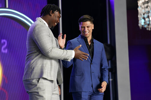 Mississippi quarterback Matt Corral, right, shakes hands with Mississippi State offensive lineman Charles Cross during the first round of the NFL football draft Thursday, April 28, 2022, in Las Vegas. (AP Photo/John Locher)