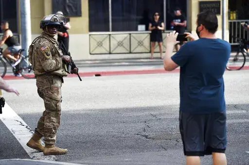 A pedestrian photographs a U.S. National Guardsman as he patrols Hollywood Blvd., May 31, 2020, in Los Angeles. The Republican leaders of the Arizona Legislature will not try to defend a new law that has been blocked by a federal judge that limits up-close filming of police, a decision that essentially ends the fight over the contentious proposal. (AP Photo/Chris Pizzello, File)