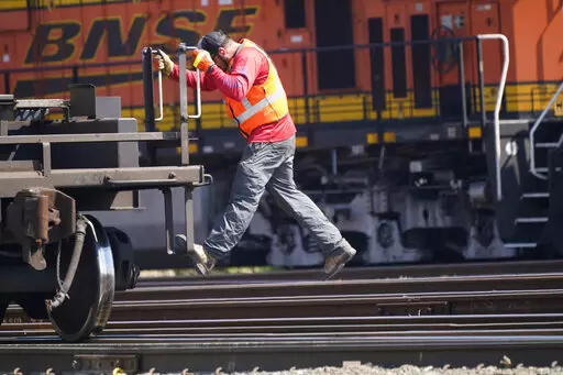 A worker rides a rail car at a BNSF rail crossing in Saginaw, Texas, Wednesday, Sept. 14, 2022. Business and government officials are preparing for a potential nationwide rail strike at the end of this week while talks carry on between the largest U.S. freight railroads and their unions. (AP Photo/LM Otero)