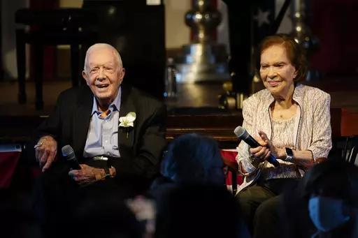 FILE- Former President Jimmy Carter and his wife former First Lady Rosalynn Carter sit together during a reception to celebrate their 75th anniversary Saturday, July 10, 2021, in Plains, Ga. In the year since Jimmy Carter first entered home hospice care, the 39th president has celebrated his 99th birthday, enjoyed tributes to his legacy and outlived his wife of 77 years. Rosalynn Carter, who died in November 2023 after suffering from dementia, spent just a few days under hospice. (AP Photo/John 