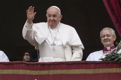 Pope Francis waves before delivering the Urbi et Orbi (Latin for 'to the city and to the world' ) Christmas' day blessing from the main balcony of St. Peter's Basilica at the Vatican, Monday Dec. 25, 2023. (AP Photo/Gregorio Borgia)