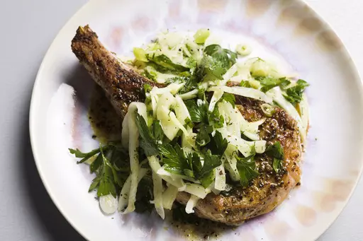 This image released by Milk Street shows a recipe for seared pork chops with fennel and herb salad. (Milk Street via AP)