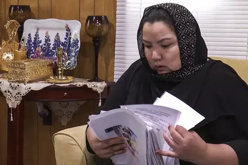 In this image from video, Zumret Dawut, a Uighur from China's western Xinjiang region who forcibly sterilized for having a third child after being released from a Xinjiang detention camp, looks at documents at her home in Woodbridge, Va., on Monday, June 15, 2020. For Dawut and other camp survivors who spoke out, the U.N.'s report on the mass detentions and other rights abuses against Uyghurs and other mostly Muslim ethnic groups in Xinjiang was the culmination of years of advocacy, and a much-w