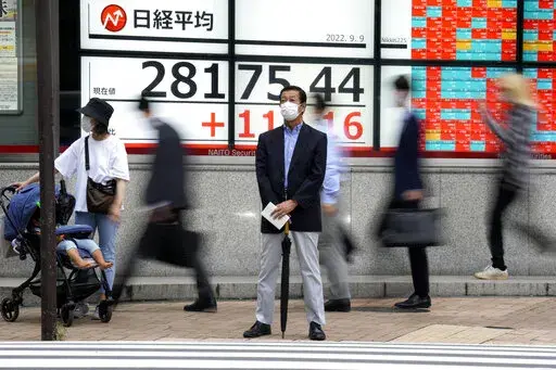 A person wearing a protective mask stands in front of an electronic stock board showing Japan's Nikkei 225 index at a securities firm Friday, Sept. 9, 2022, in Tokyo. Asian benchmarks rose Friday, cheered by gains on Wall Street as comments from the Federal Reserve chairman assured markets on the expected rate rise.(AP Photo/Eugene Hoshiko)