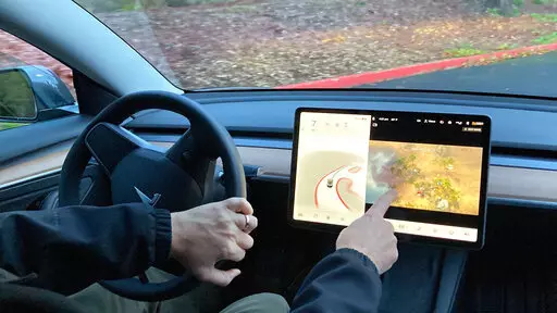 FILE - Vince Patton, a new Tesla owner, demonstrates on Dec. 8, 2021, on a closed course in Portland, Ore., how he can play video games on the vehicle's console while driving. Under pressure from U.S. auto safety regulators, Tesla has agreed to stop allowing video games to be played on center touch screens while its vehicles are moving.  (AP Photo/Gillian Flaccus, File)
