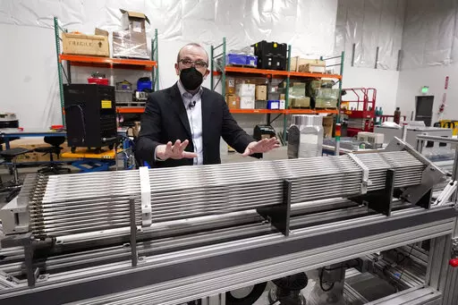 Chris Levesque, president and CEO of TerraPower, a company developing and building small nuclear reactors, displays a fuel assembly model, Thursday, Jan. 13, 2022, in Everett, Wash. The 5-foot model is about one-third actual length and would be vertical when in use, rather than horizontal. By cooling the reactor with liquid sodium, a metal that solidifies at well above room temperature, TerraPower says its relatively small, 345-megawatt plant will be safe and less expensive than conventional, wa