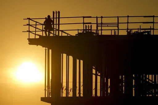 Construction workers start their day as the sun rises on the new Republic Airlines headquarters building in Carmel, Ind., Aug. 27, 2024. (AP Photo/Michael Conroy, File)