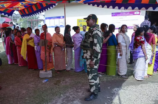 A Border Security Force soldier stands guard as women queue up to vote during a re-polling in Imphal West District, Manipur, India, Monday, April 22, 2024. Voters at some polling places in this northeastern state went back to the polls amid tight security on Monday after violence disrupted the vote last week. (AP Photo/Bullu Raj)