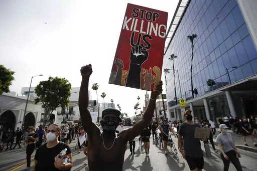 A protester carries a sign in the Hollywood area of Los Angeles on June 1, 2020, during demonstrations after the killing of George Floyd, which sparked calls for a racial reckoning to address structural racism that has created longstanding inequities impacting generations of Black Americans. Two former Minneapolis police officers charged in Floyd's death are heading to trial on state aiding and abetting counts, the third and likely final criminal proceeding in a killing that mobilized protesters
