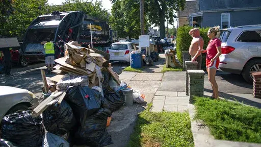 Residents wait a worker picking up debris, Monday, Sept. 6, 2021, in Passaic, NJ., from their flood damaged home in the aftermath of Hurricane Ida. (AP Photo/Eduardo Munoz Alvarez)