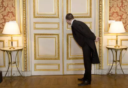 A usher looks through the key hole at the French foreign ministry in Paris, Friday March 4, 2016 during international ministerial discussions about Syria. Members of the French diplomatic corps, a mostly invisible force that guides the nation's conduct of international affairs, are dropping their traditional reserve to go on strike Thursday, angered by a planned reform they fear will hurt their careers and France's standing in the world. (AP Photo/Jacques Brinon, File)