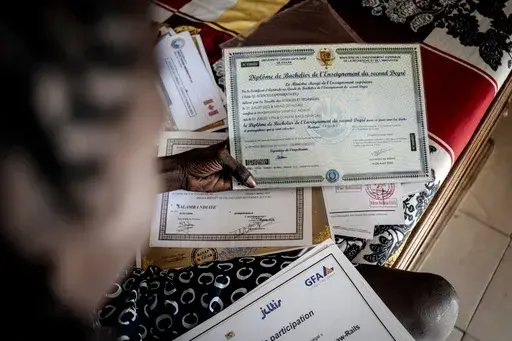 CORRECTS FAMILY NAME TO NDIAYE - Salamba Ndiaye, a 28-year-old who tried to migrate to Europe twice, checks her school certificates at her house in Thiaroye-Sur-Mer, Senegal, Friday, Aug. 23, 2024. Ndiaye is one of thousands of young Senegalese who try to flee poverty and the lack of job opportunities in the West African country each year to head to Spain. More than 22,300 people have landed on the Canary Islands from January to mid-August this year, (AP Photo/Annika Hammerschlag)