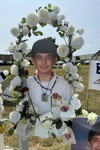 A poster with an image of shooting victim Christian Angulo is displayed at a memorial outside Apalachee High School, Tuesday, Sept. 10, 2024, in Winder, Ga. (AP Photo/Charlotte Kramon)