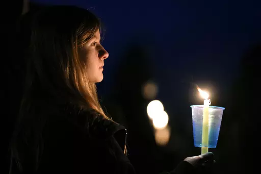 A local resident prays during a candlelight vigil following a shooting at Perry High School, Jan. 4, 2024, in Perry, Iowa. An Iowa principal who put himself in harm's way to protect students during a school shooting earlier this month has died. Caldwell Parrish Funeral Home & Crematory confirmed the death of Perry High School Principal Dan Marburger after the family announced it on a GoFundMe page. Marburger died Sunday morning, Jan. 14 after he was critically injured during the Jan. 4 attack. (