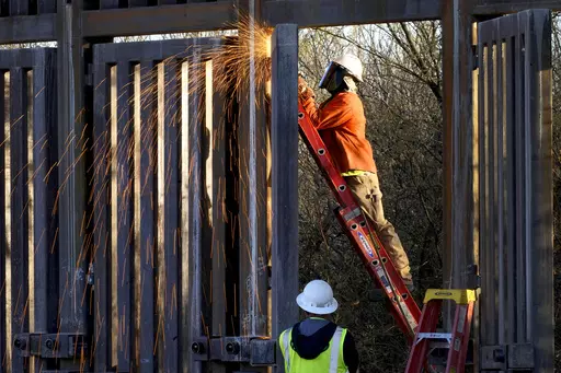 Crews construct a section of border wall in San Bernardino National Wildlife Refuge, Tuesday, Dec. 8, 2020, in Douglas, Ariz. Construction of the wall along the U.S.-Mexico border under former President Donald Trump toppled untold numbers of saguaro cactuses in Arizona, put endangered ocelots at risk in Texas and disturbed Native American burial grounds, Congress' official watchdog said Thursday, Sept. 7, 2023. (AP Photo/Matt York, File)