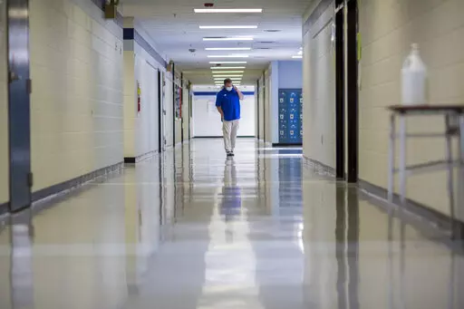 FILE - A middle school principal walks the empty halls of his school as he speaks with one of his teachers to get an update on her COVID-19 symptoms, Friday, Aug., 20, 2021, in Wrightsville, Ga. On Monday, Dec. 27, 2021, U.S. health officials cut isolation restrictions for Americans who catch the coronavirus from 10 to five days, and also shortened the time that close contacts need to quarantine. (AP Photo/Stephen B. Morton, File)