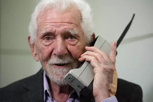 Marty Cooper, the inventor of first commercial mobile phone, poses for the press with a Motorola DynaTAC 8000x, during an interview with The Associated Press at the Mobile World Congress 2023 in Barcelona, Spain, Monday, Feb. 27, 2023. The four-day show kicks off Monday in a vast Barcelona conference center. It's the world's biggest and most influential meeting for the mobile tech industry. (AP Photo/Joan Mateu Parra)