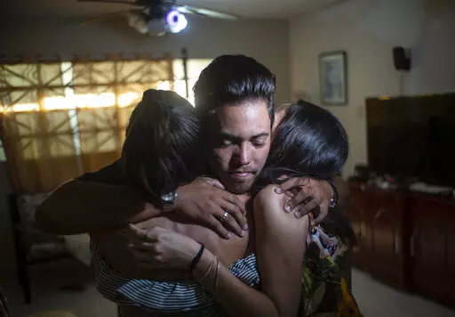 Marcos Marzo hugs two of his friends who came to say goodbye upon receiving the news that he had obtained a permit to travel to the United States, in Havana, Cuba, Wednesday, Jan 25, 2023. Now in the U.S., his dream is to do a master’s degree at the Massachusetts Institute of Technology and work as an engineer, which he says is his passion. (AP Photo/Ramon Espinosa)