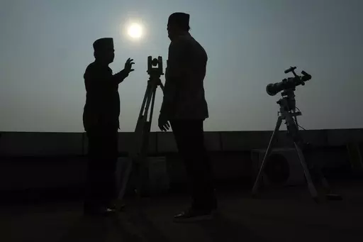 Officials are silhouetted as they use a telescope to scan the horizon for a crescent moon that will determine the beginning of the holy fasting month of Ramadan in Jakarta, Indonesia, Wednesday, March. 22, 2023. (AP Photo/Achmad Ibrahim, File)