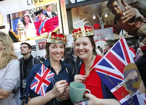 Molly Davis, left, and Amanda D'Aquila join a large crowd in New York's Times Square to watch the royal wedding, April 29, 2011. The pomp, the glamour, the conflicts, the characters — when it comes to the United Kingdom’s royal family, the Americans can’t seem to get enough. (AP Photo/Mark Lennihan, File)