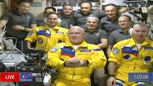 In this frame grab from video provided by Roscosmos, Russian cosmonauts Sergey Korsakov, Oleg Artemyev and Denis Matveyev are seen during a welcome ceremony after arriving at the International Space Station, Friday, March 18, 2022, the first new faces in space since the start of Russia’s war in Ukraine. The crew emerged from the Soyuz capsule wearing yellow flight suits with blue stripes, the colors of the Ukrainian flag. (Roscosmos via AP)
