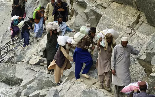 Local residents cross a portion of road destroyed by floodwaters in Kalam Valley in northern Pakistan, Sunday, Sept. 4, 2022. Officials warned Sunday that more flooding was expected as Lake Manchar in southern Pakistan swelled from monsoon rains that began in mid-June and have killed nearly 1,300 people. (AP Photo/Sherin Zada)