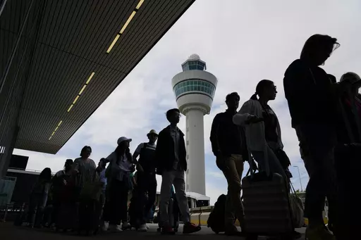Travelers wait in long lines outside the terminal building to check in and board flights at Amsterdam's Schiphol Airport, Netherlands, on June 21, 2022. A judge ruled Wednesday April 5, 2023 that the Dutch government cannot order Amsterdam's Schiphol Airport, one of Europe's busiest aviation hubs, to reduce the number of flights from 500,000 per year to 460,000, dealing a blow to efforts to cut emissions and noise pollution.(AP Photo/Peter Dejong, File)