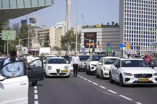 Israelis stand still next to their cars on a main road as a two-minute siren sounds in memory of victims of the Holocaust in Tel Aviv, Israel, Thursday, April 28, 2022. Holocaust remembrance day is one of the most solemn on Israel's calendar with restaurants and places of entertainment shut down, and radio and TV programming focused on Holocaust documentaries and interviews with survivors. (AP Photo/Ariel Schalit)