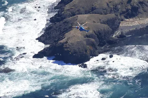 A helicopter hovers over the tip of Shiretoko Peninsula in northern Japan of Hokkaido to conduct a search operation Monday, April 25, 2022. Rescuers continue the search operation for the missing since a tour boat carrying 26 people apparently sank off far northeastern Japan. (Kyodo News via AP)